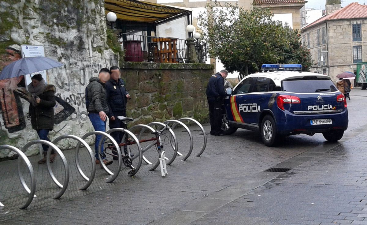 Un hombre hablando con un agente de la Policía Nacional delante de una bicicleta sin las ruedas
