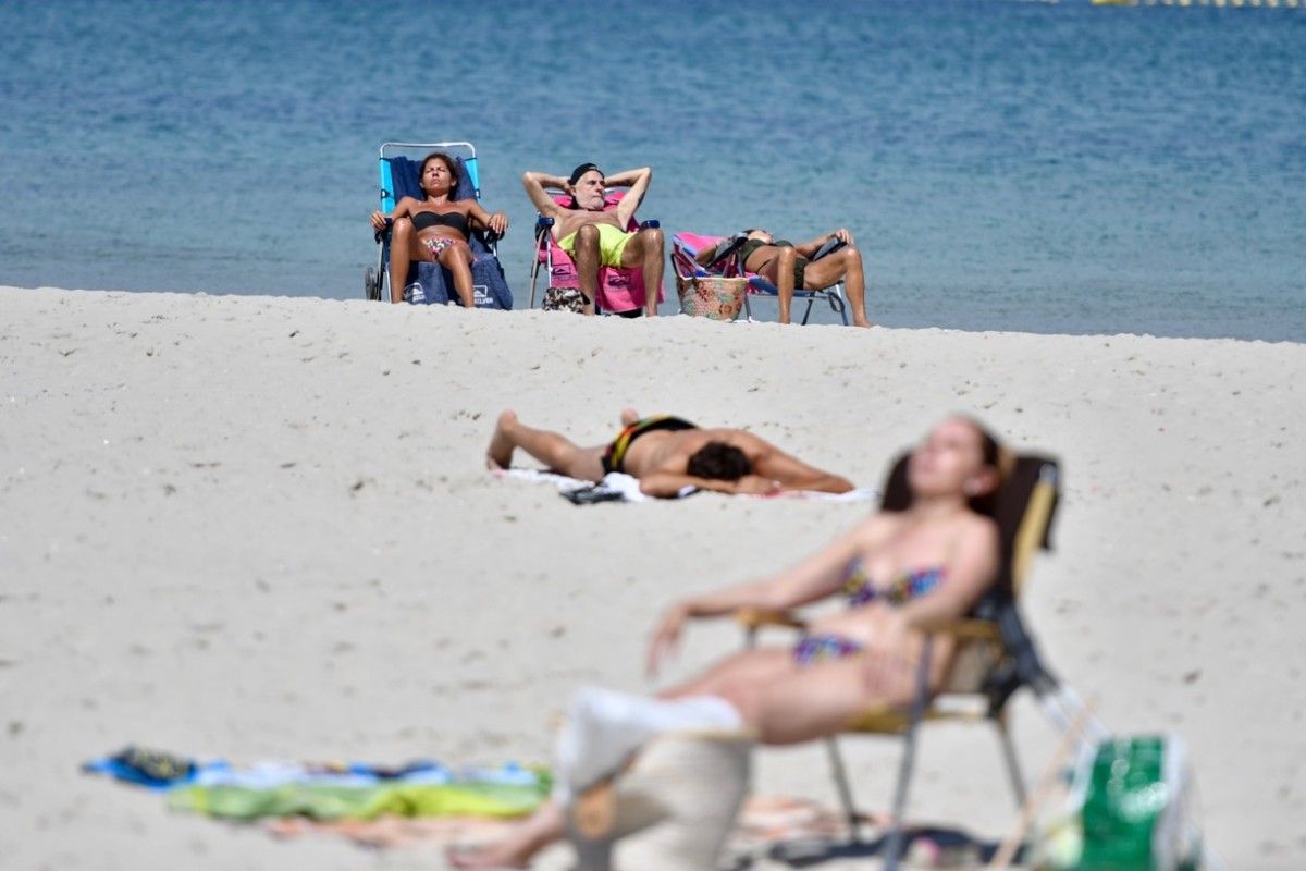 Gente paseando y tomando sol en la playa en Sanxenxo