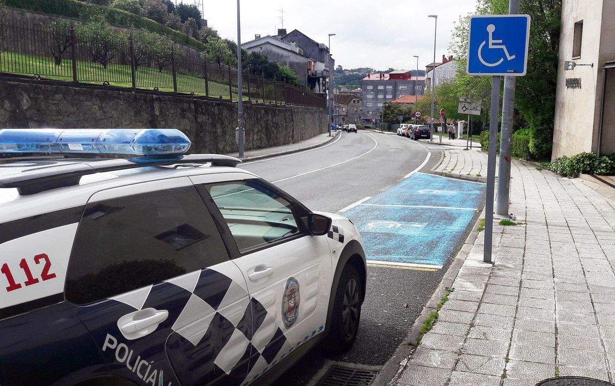 Policía Local de Poio delante de un espacio de aparcamiento reservado para personas con  movilidad reducida