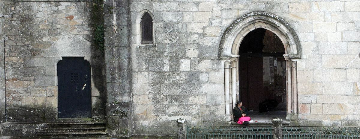 Una persona pidiendo limosna en la puerta de una iglesia