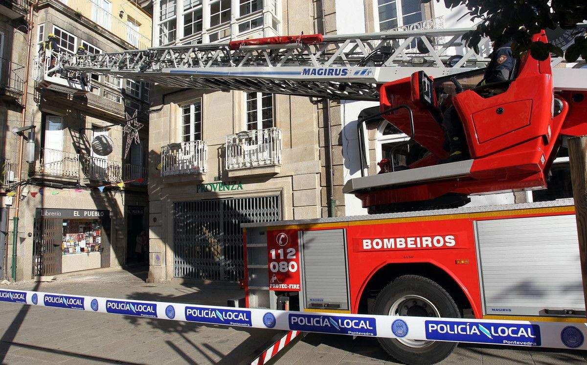 Unha pedra de grandes dimensións despréndese da fachada da librería El Pueblo na rúa San Román