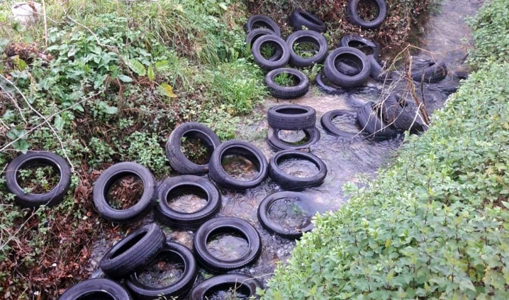 Vertido de neumáticos en un regato en el Camiño da Bouza
