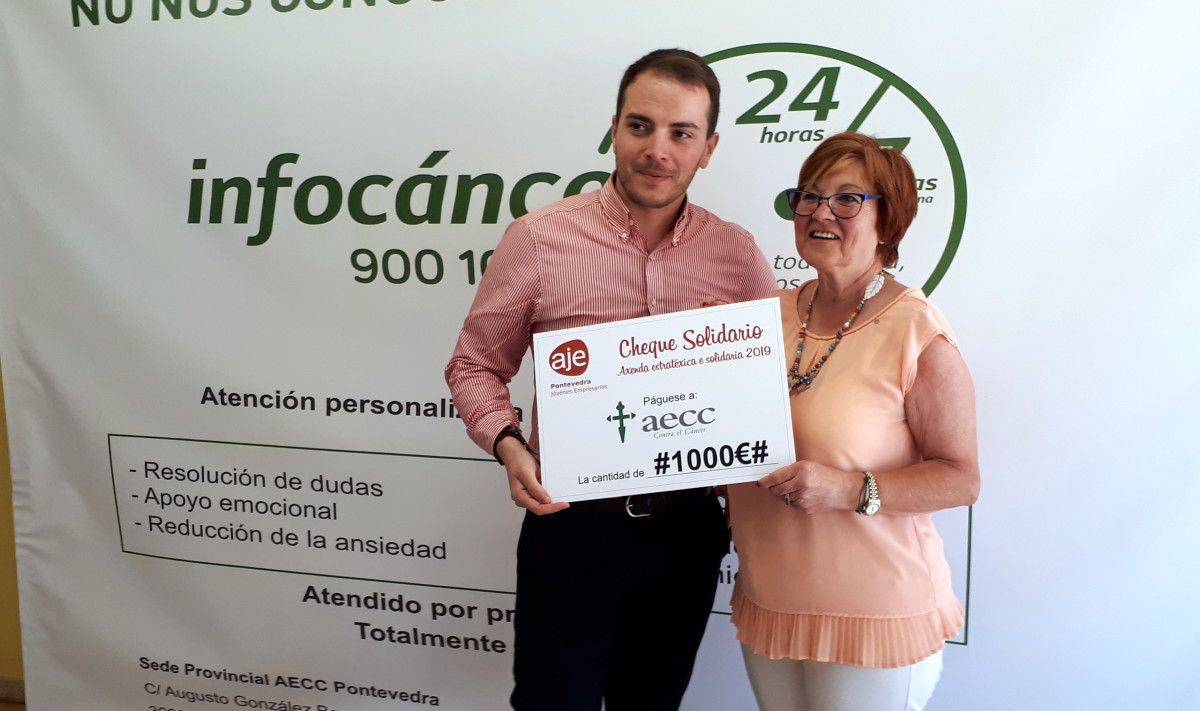 Jesús Rey, presidente de AJE Pontevedra, entrega o cheque solidario a Josefa Crespo, presidenta de AECC
