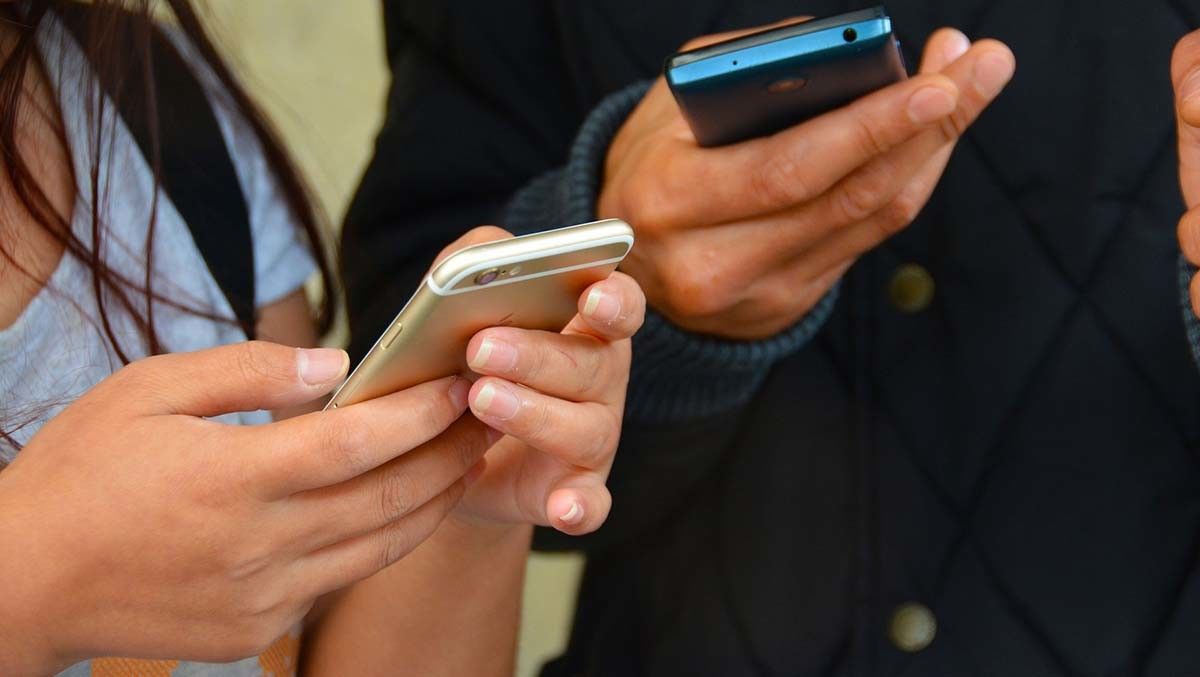 Dúas persoas utilizando un teléfono móbil