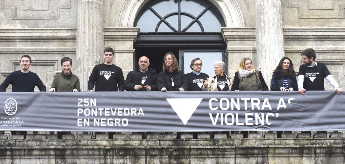 Representantes de los grupos políticos en el balcón con la pancarta del 25N