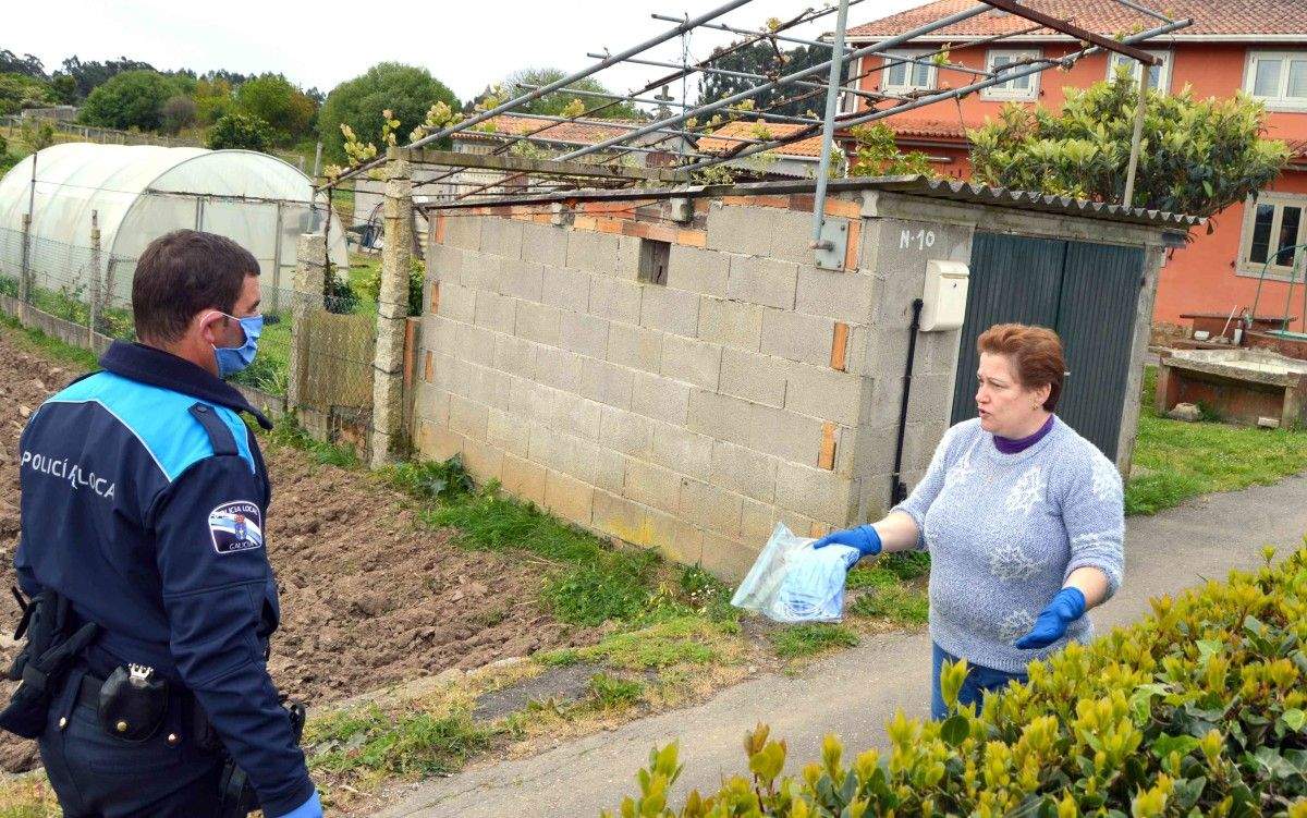 Un policía local de Sanxenxo entrega máscaras de protección a unha veciña