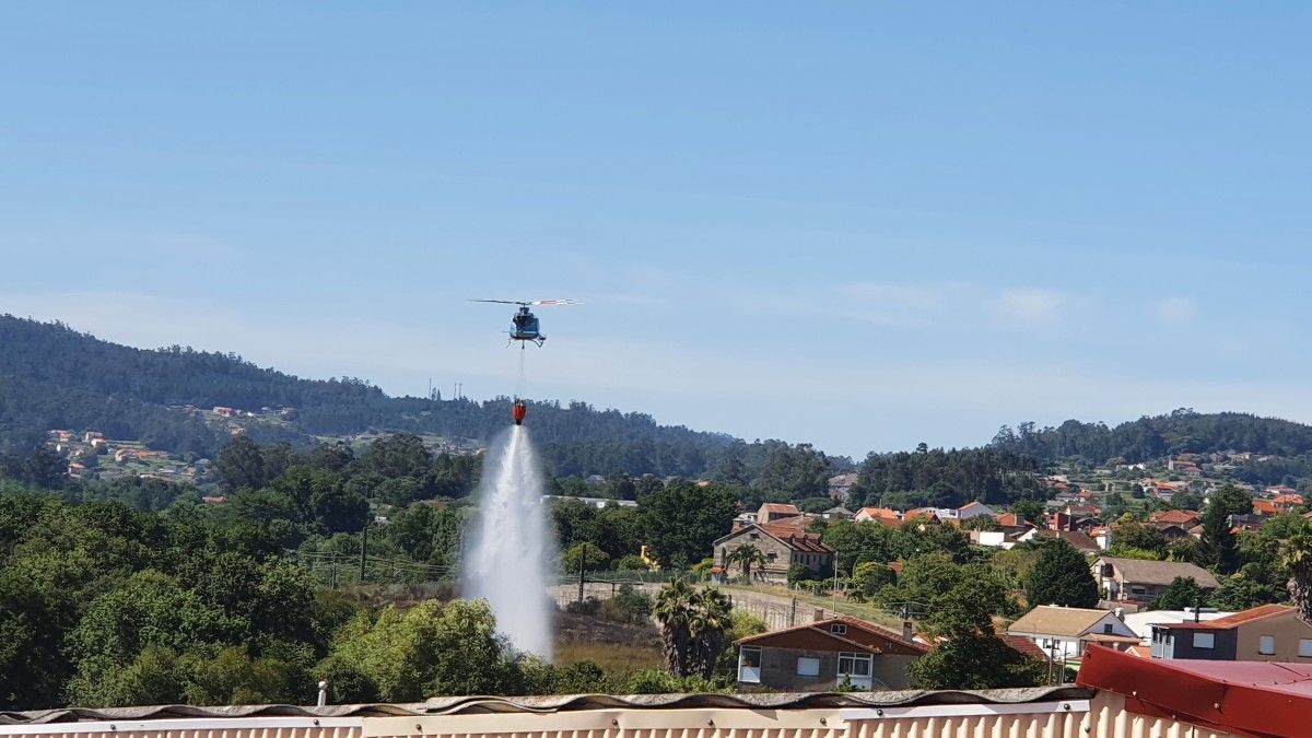 O helicóptero descarga auga sobre o incendio forestal na Gándara