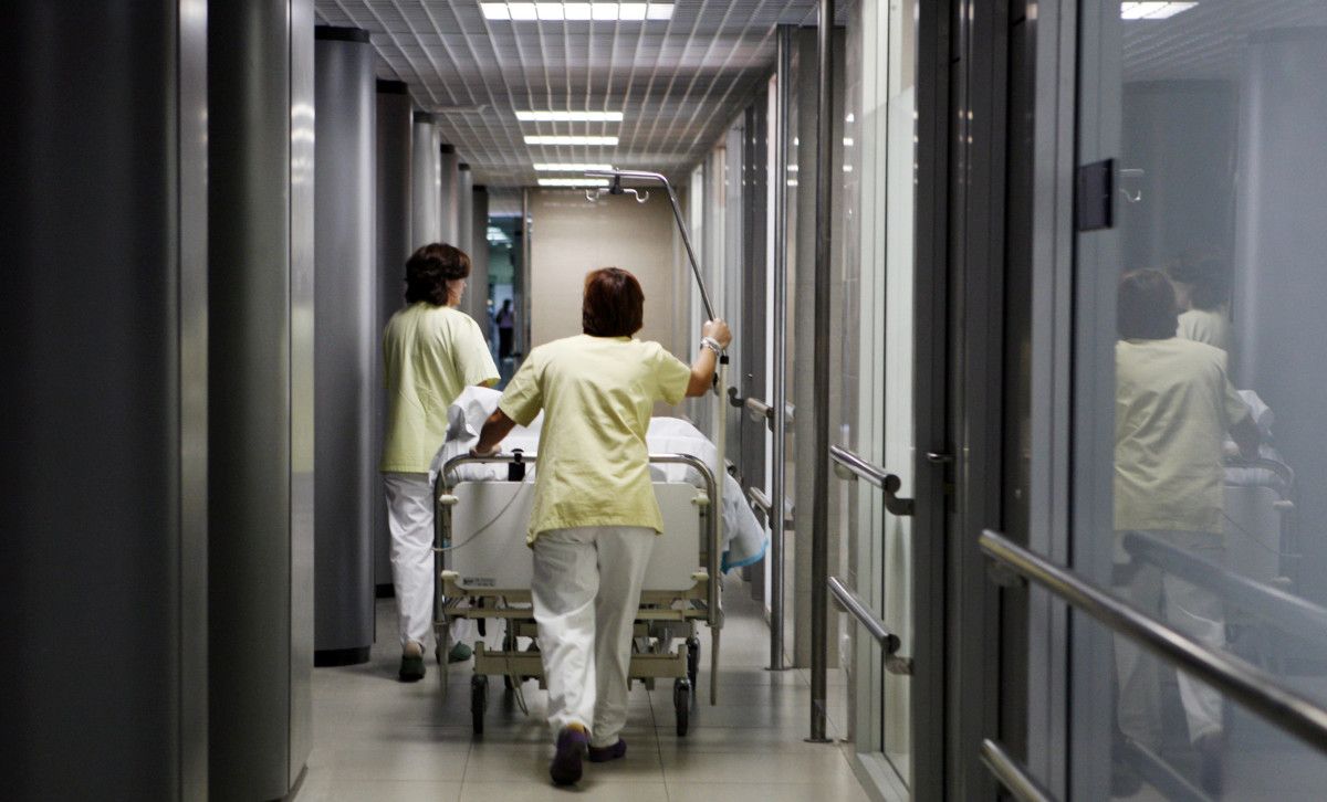 Persoal sanitario cun paciente nunha cama hospitalaria
