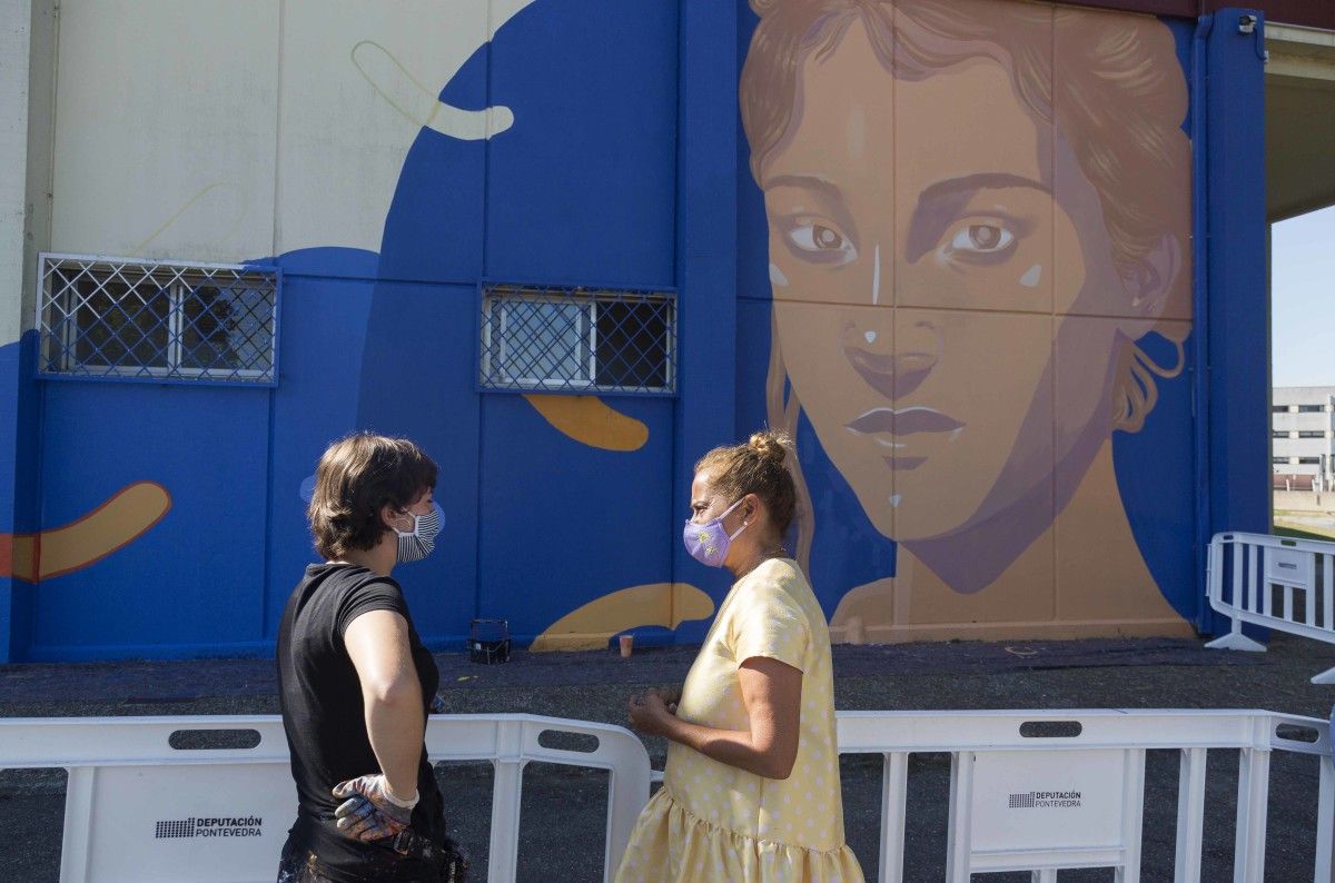 A presidenta Carmela Silva fala coa artista Lidia Cao diante do mural