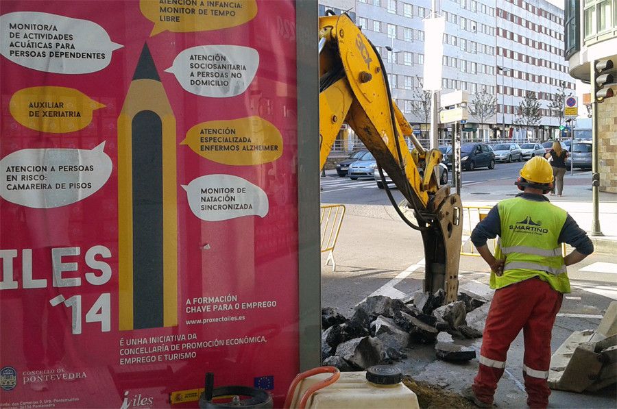 Un traballador fronte ao cartaz da ILES (Iniciativa local de emprego social)