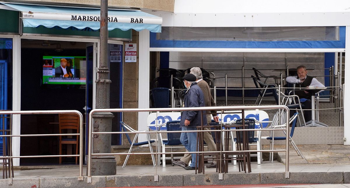 Dúas persoas pasean por diante dun local de hostalería en Sanxenxo