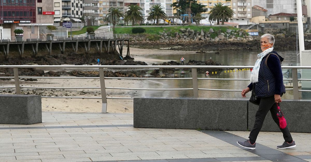 Una mujer con mascarilla paseando por Sanxenxo