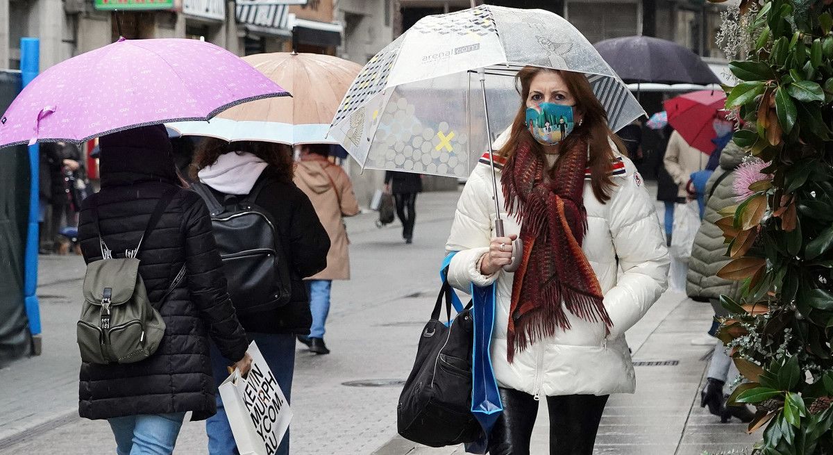 Gente con mascarillas en un día lluvioso
