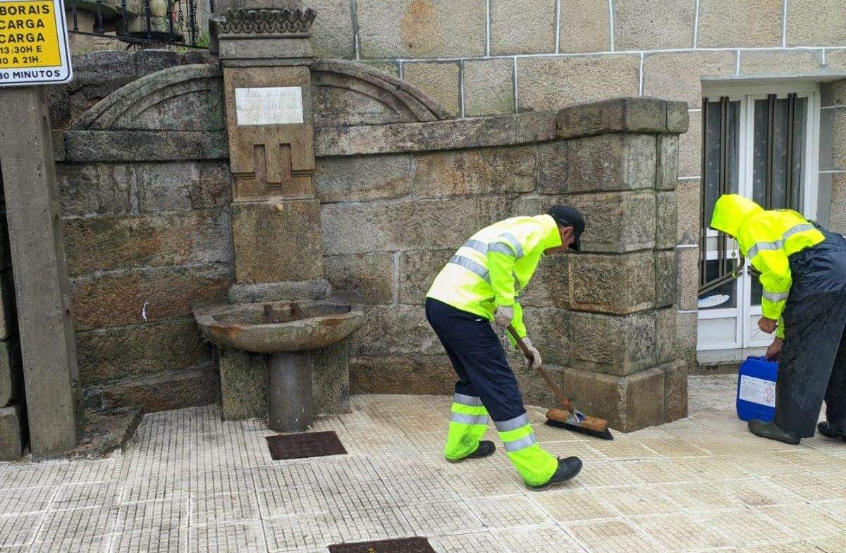 Operarios municipais limpando unha fonte en Combarro