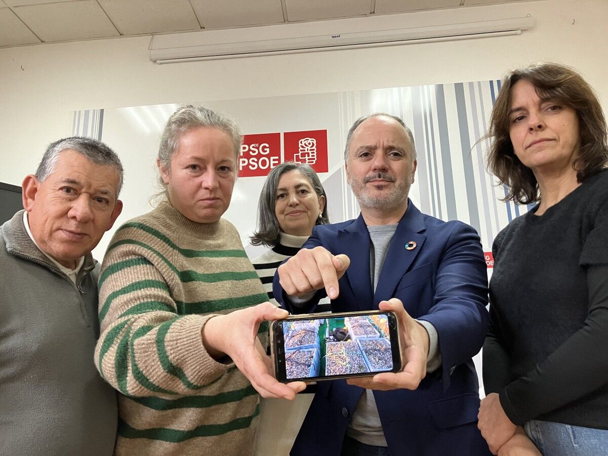 Regades e mariscadoras amosan unha foto do marisco morto recollido dos bancos marisqueiros do fondo da ría