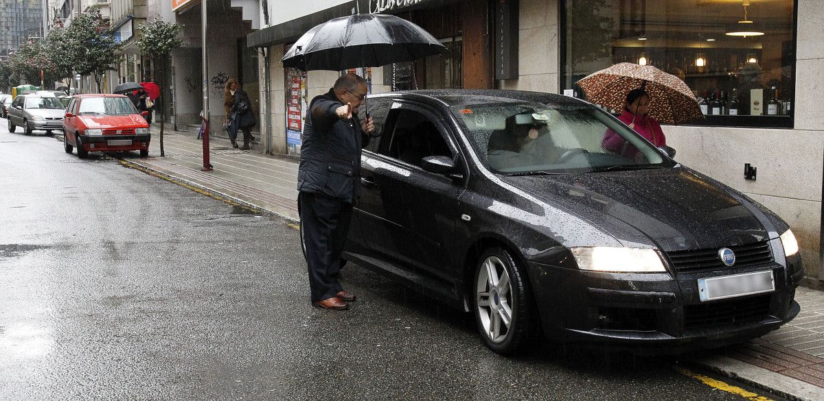 Coches aparcados enriba da beirarrúa na rúa García Camba 