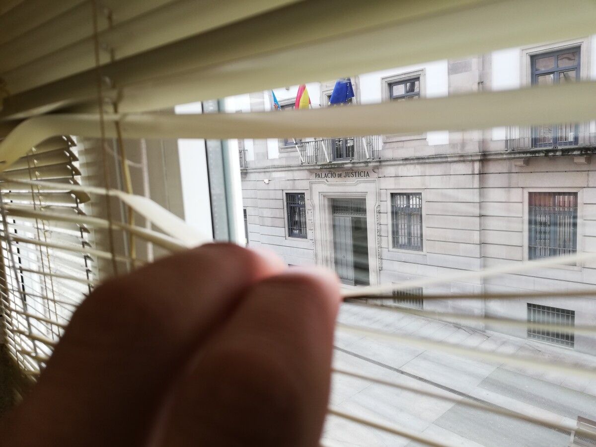 Unha persoa observando a fachada da Audiencia de Pontevedra a través dunha fiestra