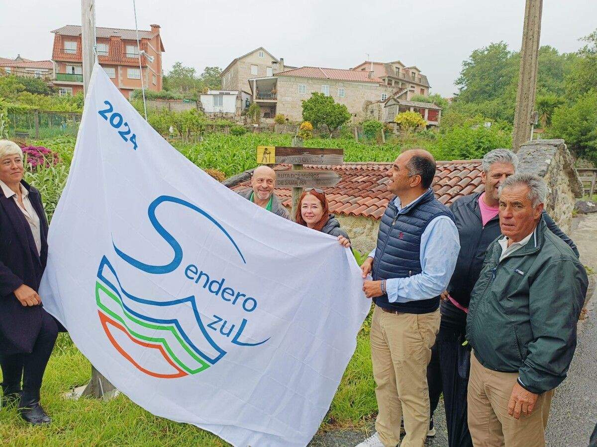 Los vecinos de Samieira izan las nuevas banderas de los Senderos Azules en las rutas del Laño y de los Muíños