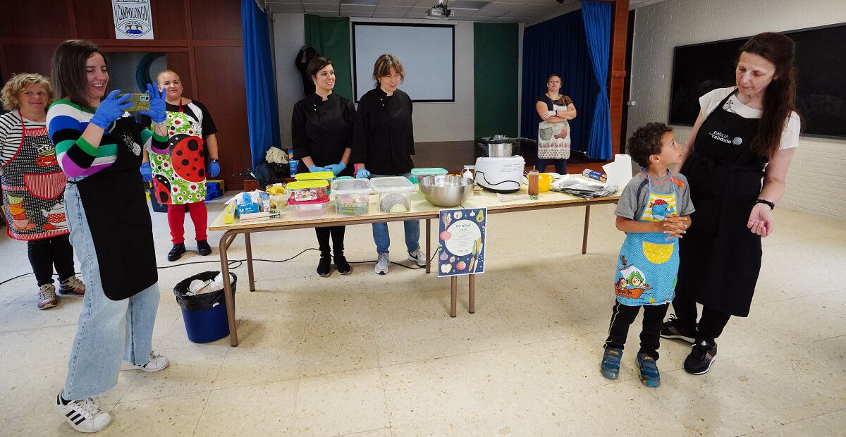Actividade "Horta Chef" no CEP Campolongo con Iria Asorey (co móbil), as chefs de Pontetapas Carolina e Laura García (tras a mesa) e Maria Rodríguez (á dta. da imaxe)