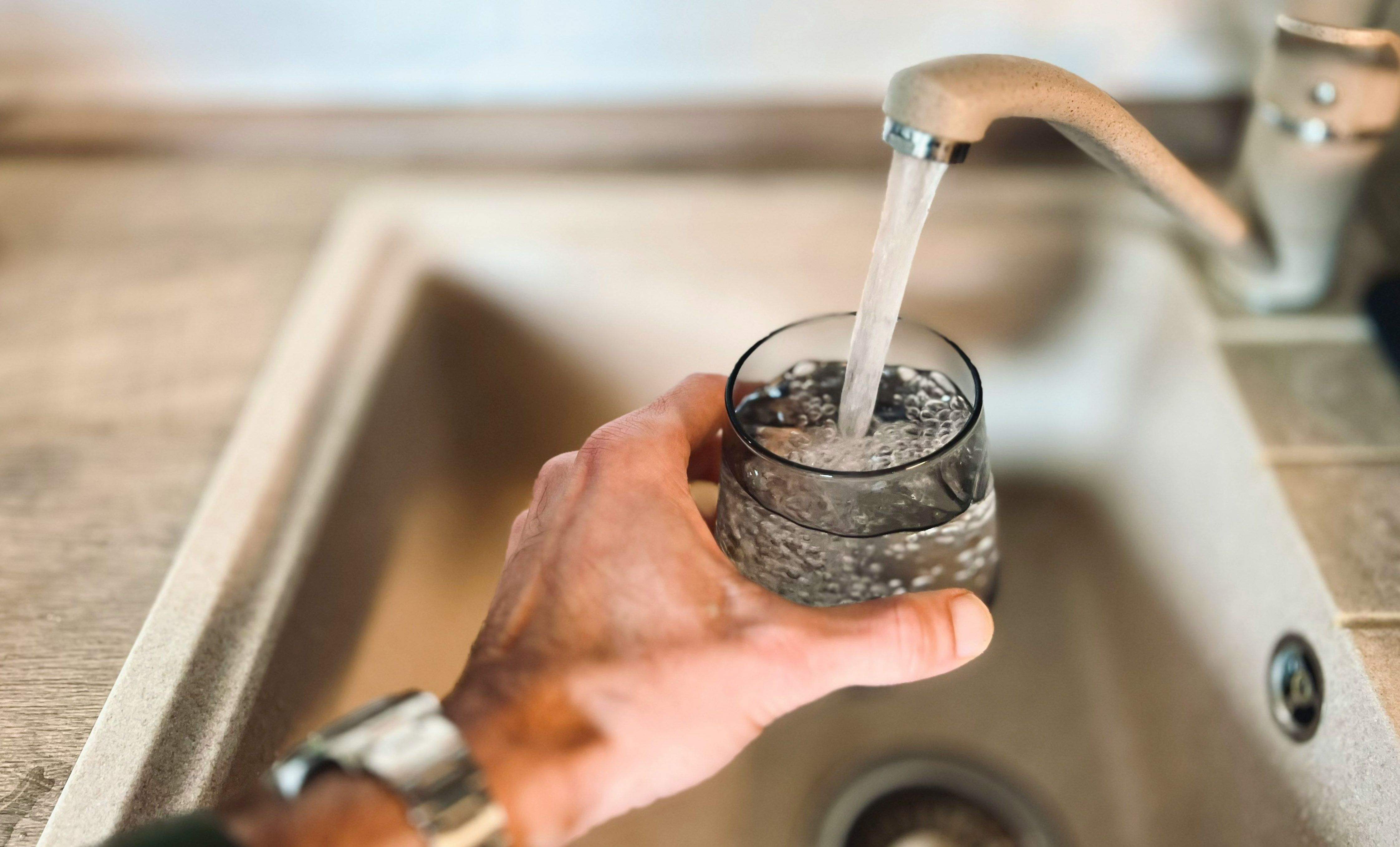 Unha persoa enchendo un vaso de auga