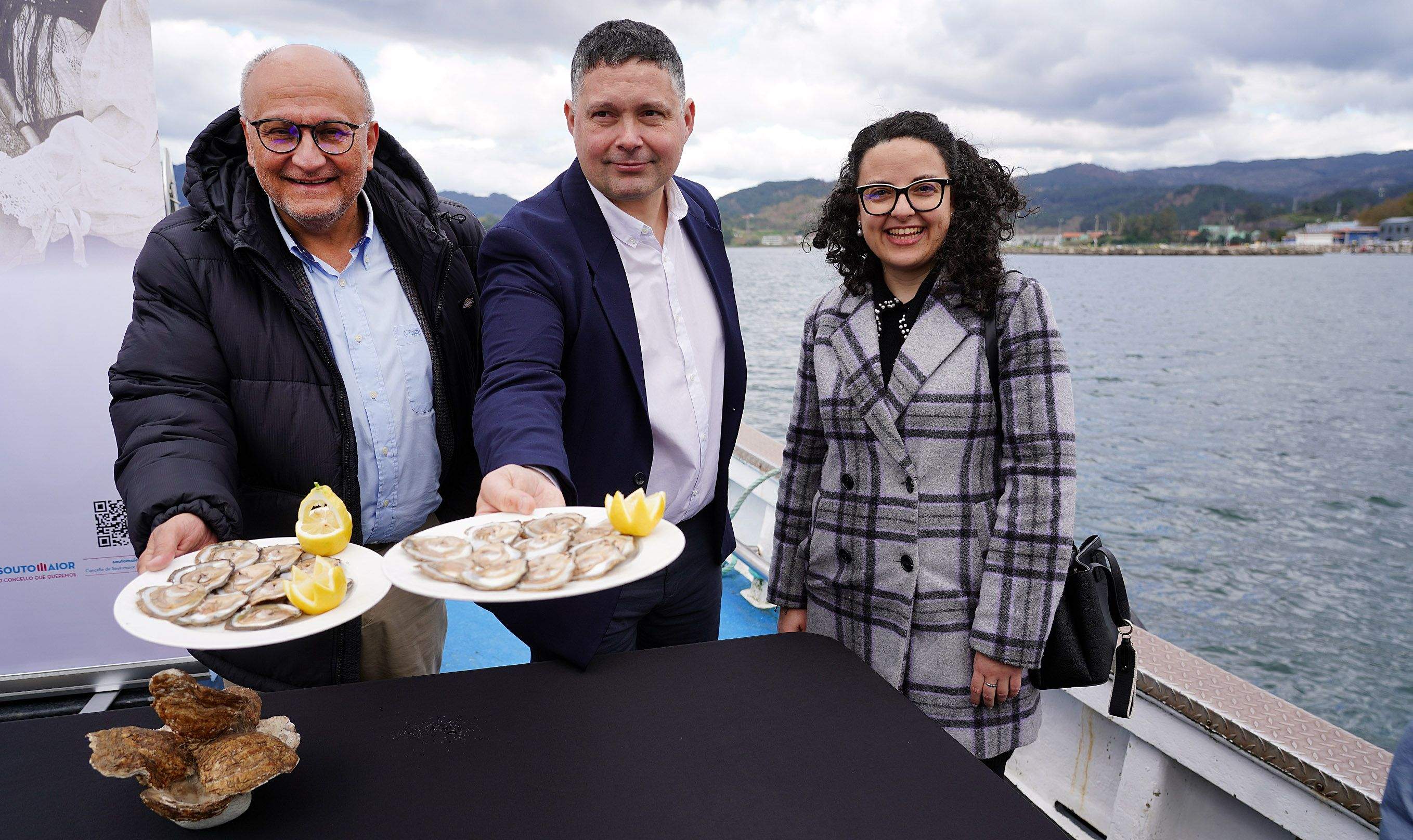 Abel Losada, Manu Lourenzo e Silvia Cernadas, na presentación da XXXVII Festa da Ostra de Arcade sobre un bateeiro