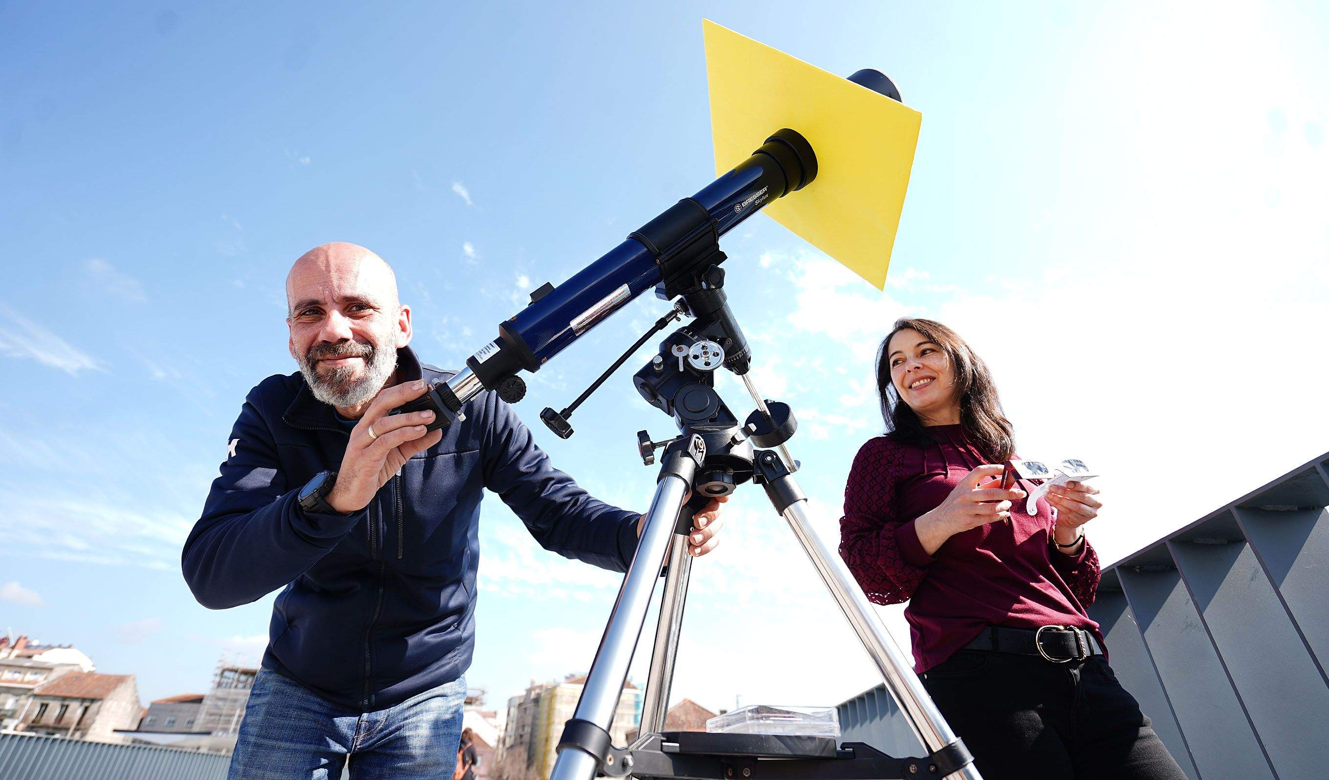 Igor Piñeiro, con un telescopio refractor con filtro para ver el Sol, y Diana Couselo, con unas "gafas de eclipse" en el puente de O Burgo