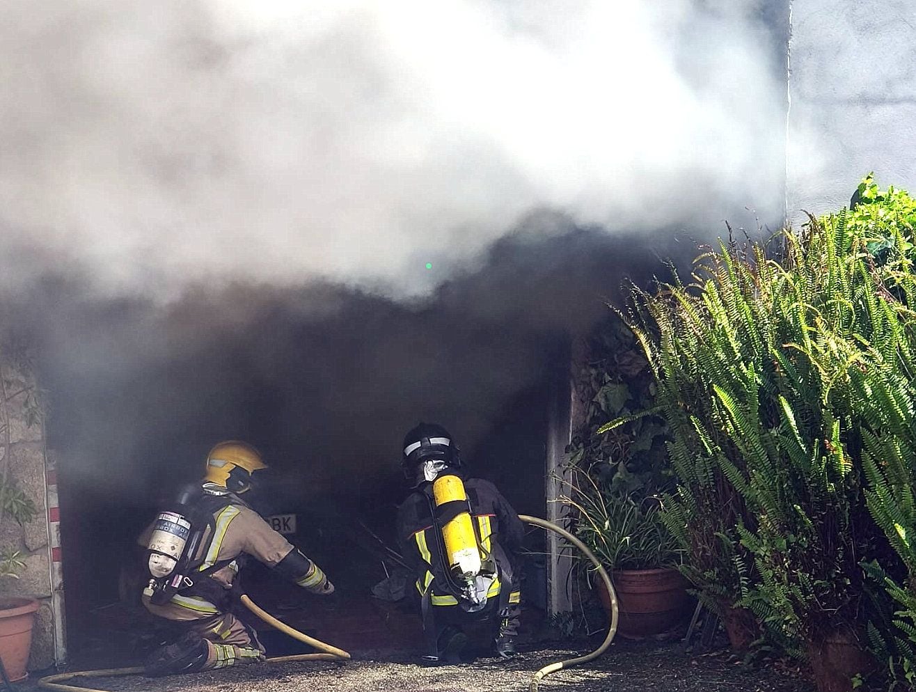 Integrantes do servizo de Emerxencias de Cambados apagando o incendio no garaxe