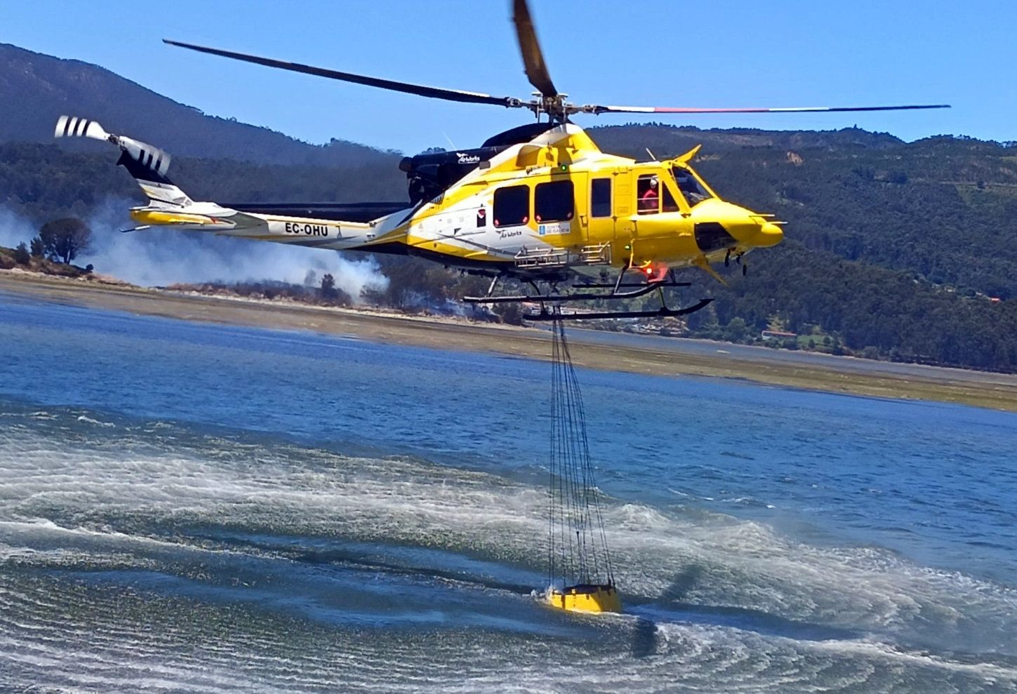 Helicóptero intentando sofocar el incendio en el islote de As Alvedosas