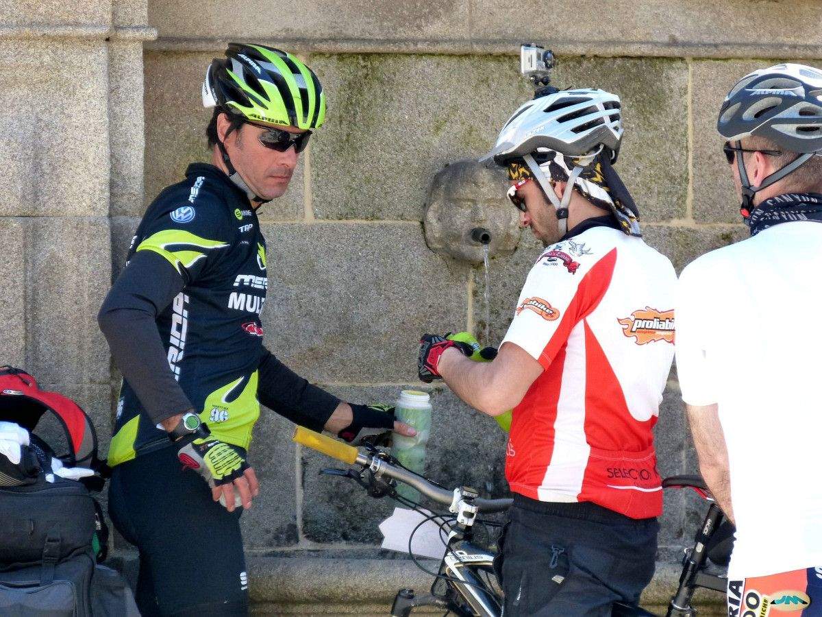Unos ciclistas bebiendo agua de la fuente