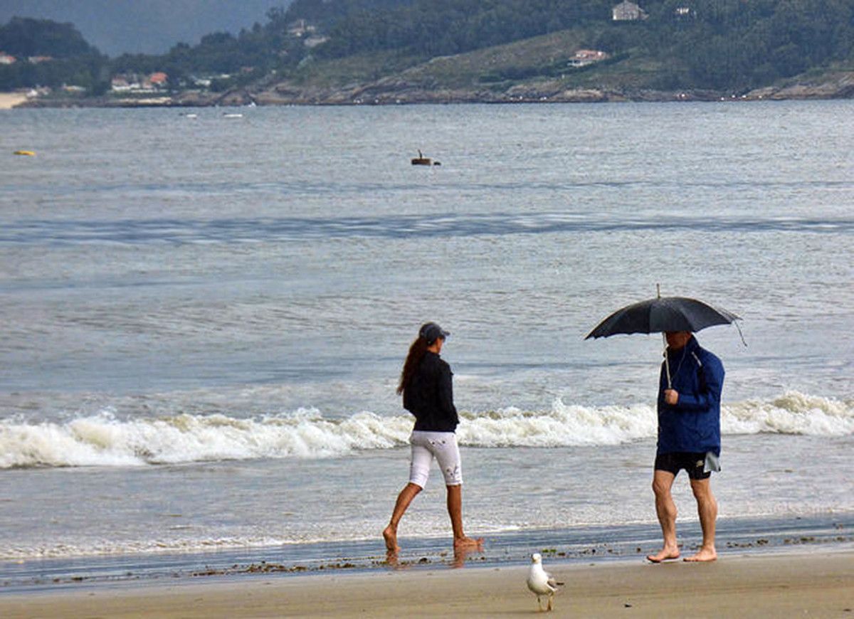 Paseo pola praia baixo a chuvia