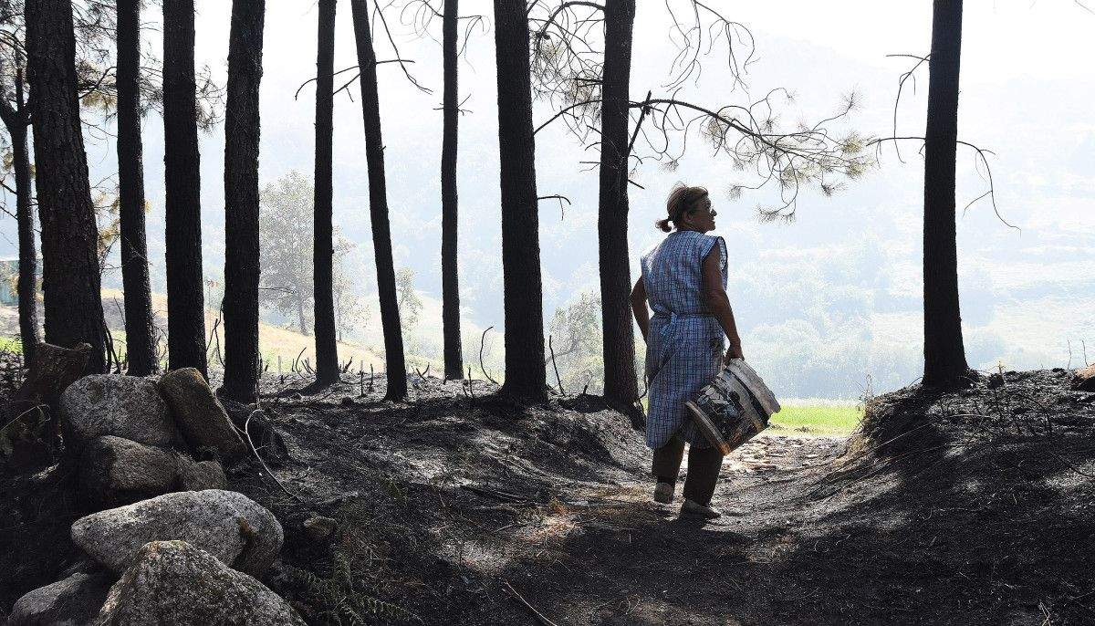 María del Placer Barbeito, veciña de Almofrei que axuda a apagar o lume cun caldeiro María del Placer Barbeito, veciña de Almofrei que axuda a apagar o lume cun caldeiro